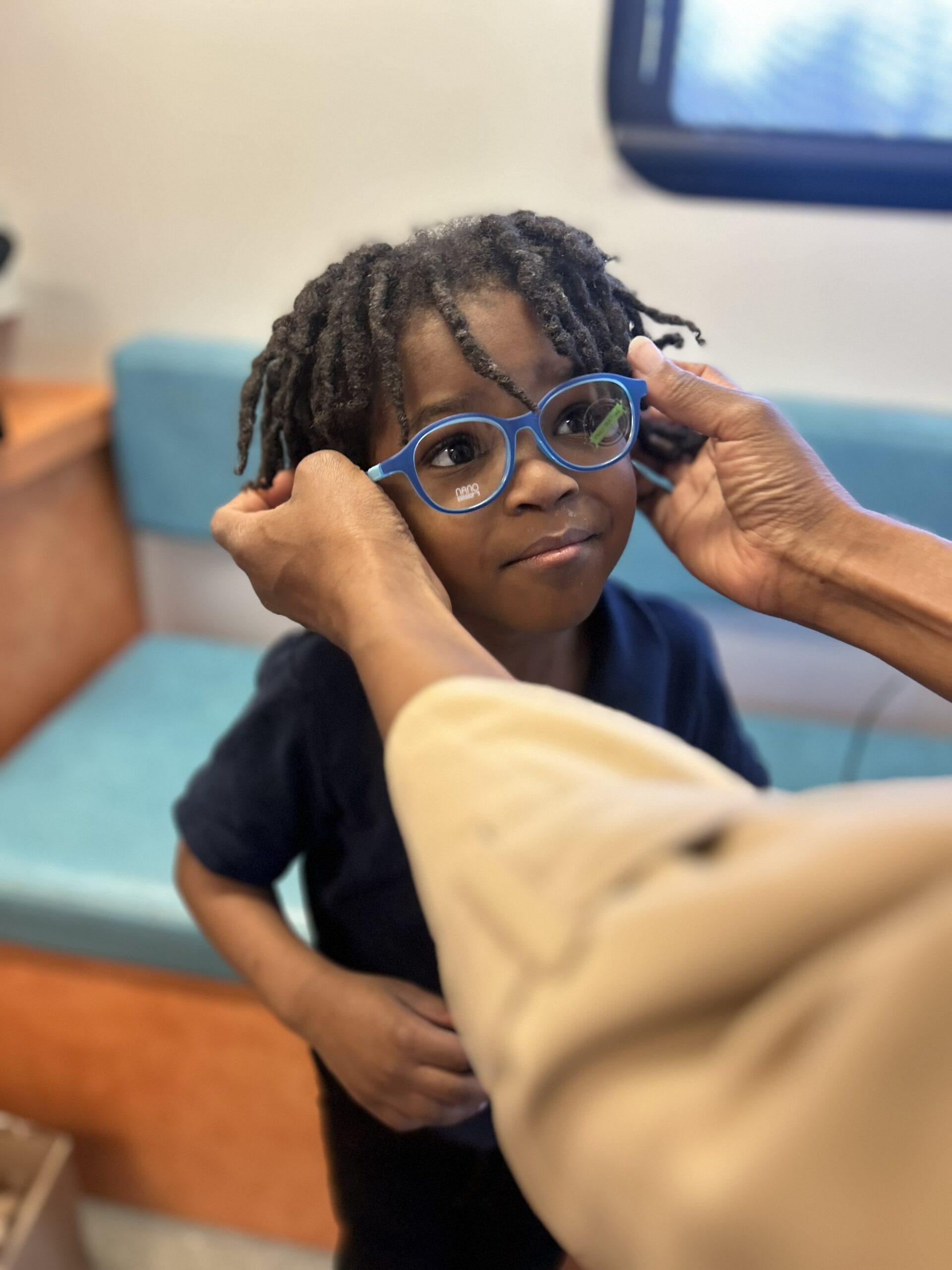A child being fitted with new blue eyeglasses