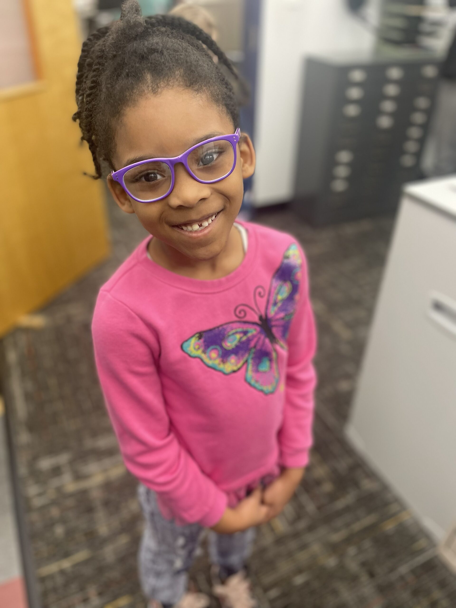 A smiling KVFL student wearing purple prescription glasses